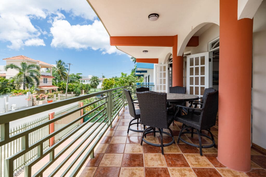 An elegant covered balcony with arched openings and a large dining table, perfect for group gatherings in the exclusive Sea Beach Colony neighborhood of Rincon.