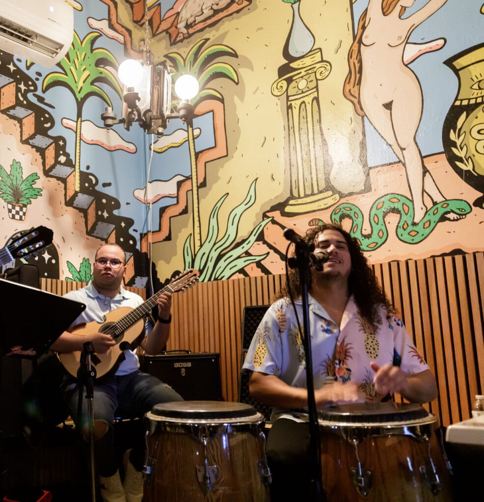 A vibrant scene of live musicians performing with drums and guitars near Casa Bonita, highlighting the authentic local culture and entertainment available to guests during their stay.